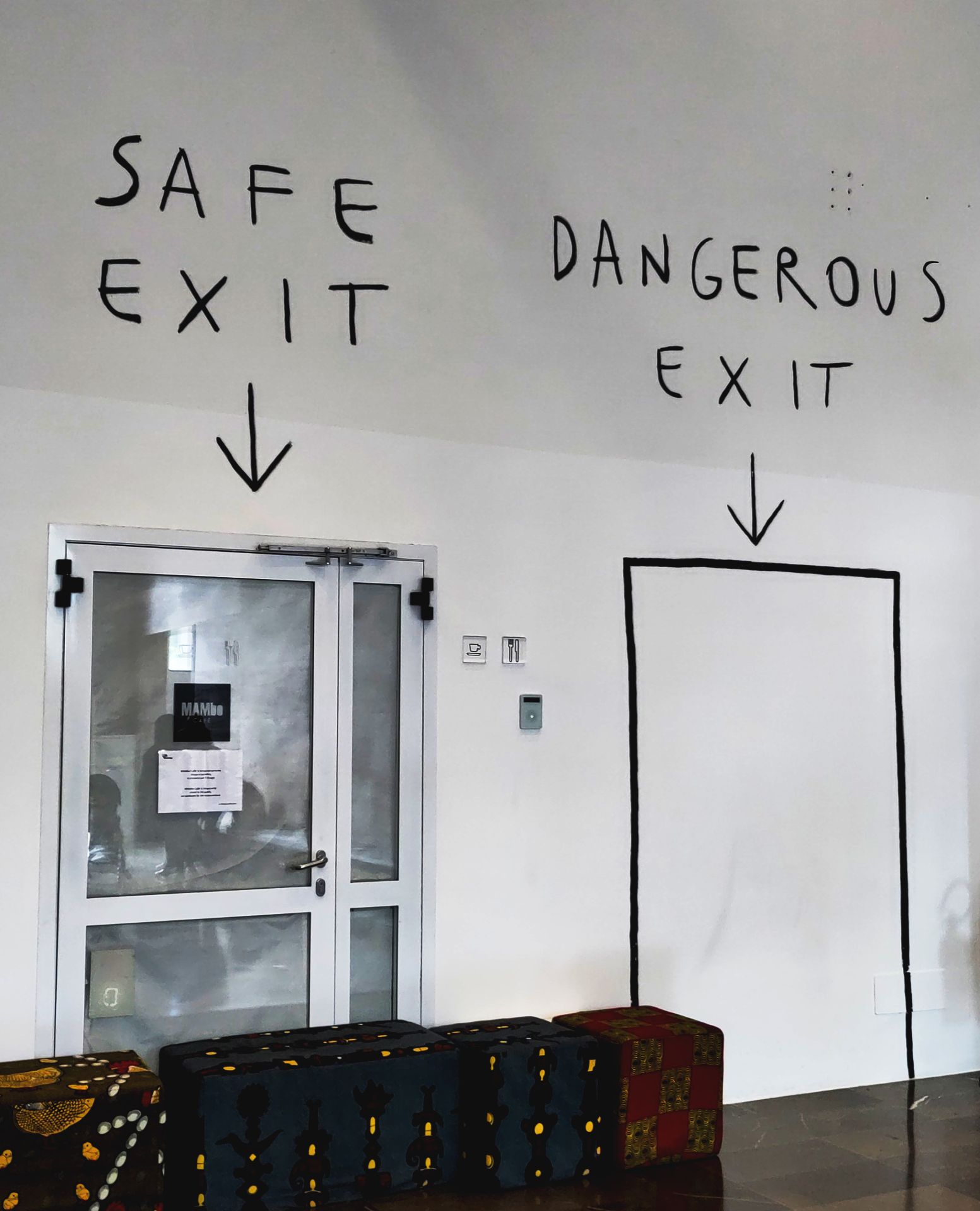 A door with Safe Exit marked above it. A rectangle of the same size as the door painted one meter further and marked Dangerous Exit (because it's not a door, it's the wall!)