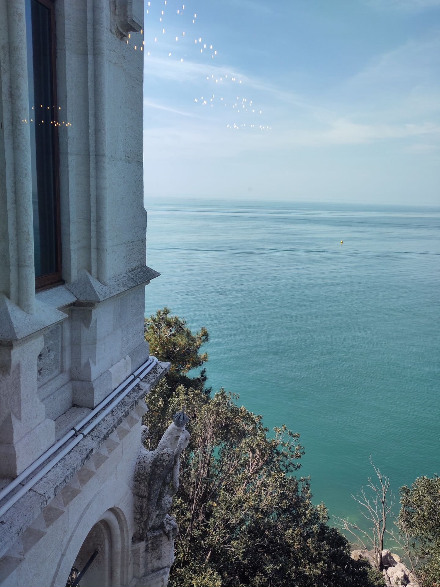The sea, as seen from a window of the castle, with only a bush separating the building from the water.